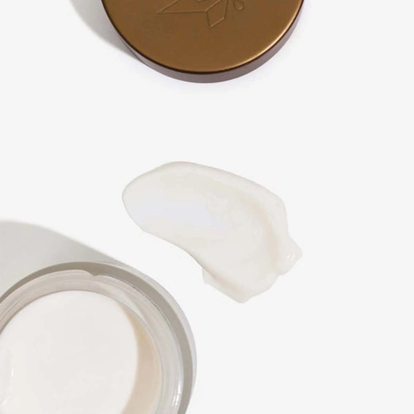 Æsken med CBD Anti-Aging Cream + Retinol ligger åben ved siden af låget og en klat af cremen.