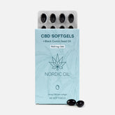 CBD-softgels i en lyseblå Nordic Oil-emballage med sortkommen frøolie og to sorte softgels ved bunden.