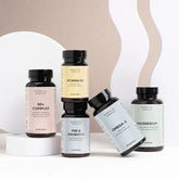 Fem Nordic Oil Essentials kosttilskud i forskellige flasker (50+ Complex, Vitamin D3, Pre & Probiotic, Omega-3, Magnesium) på en lys beige og hvid baggrund.