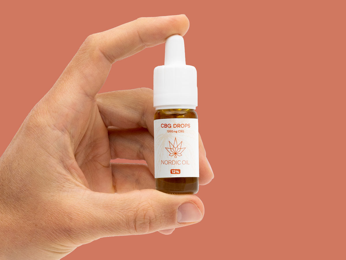 Den ene hånd holder en flaske CBG-olie (12%)