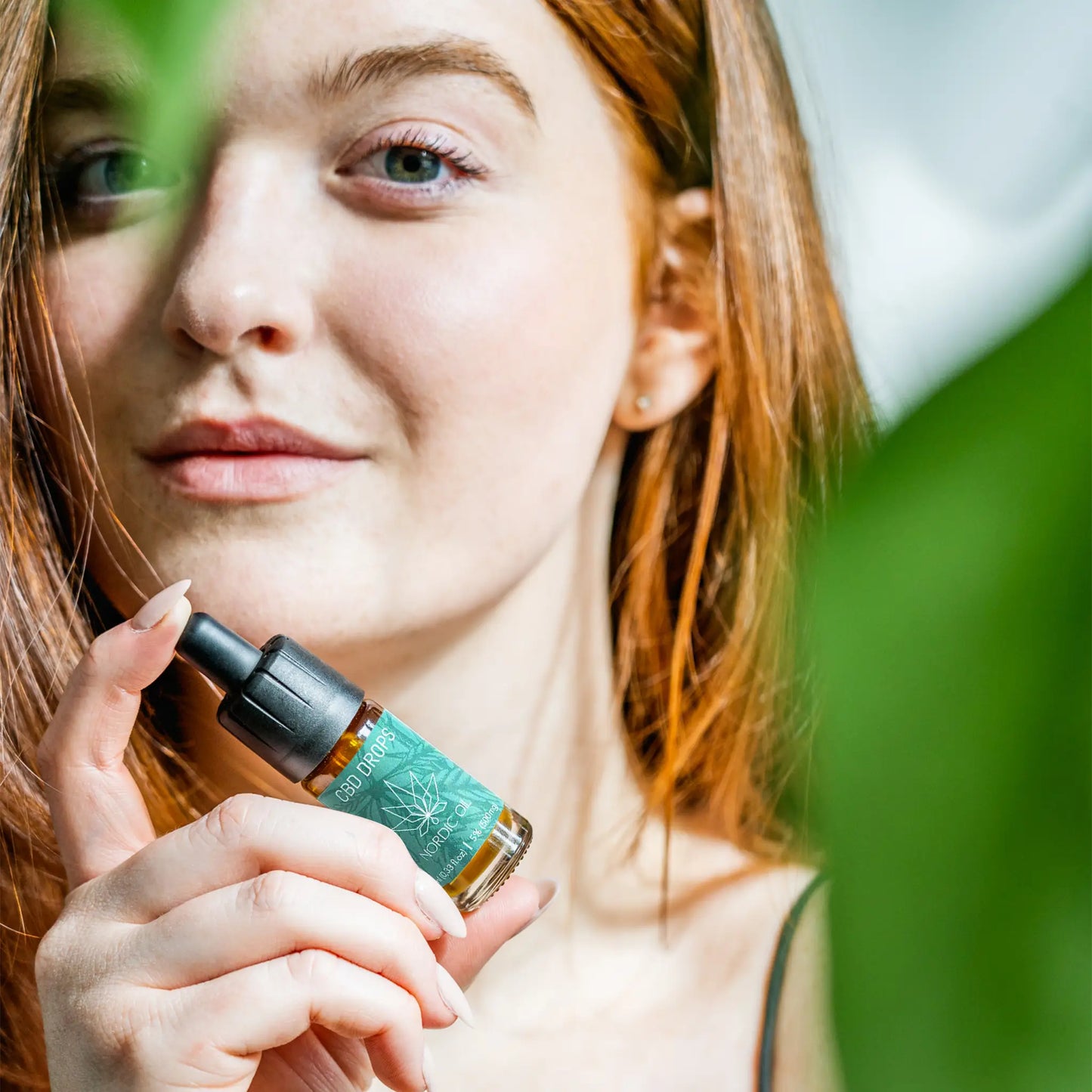 En kvinde holder en flaske med 5% CBD Oil Classic fra Nordic Oil i hånden.