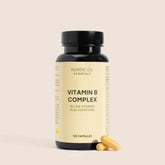 Nordic Oil Essentials Vitamin B Complex-flaske med 120 kapsler og to gule kapsler ved siden af.