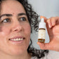En kvinde holder en flaske CBD-olie med 20% curcumin ved siden af sit ansigt