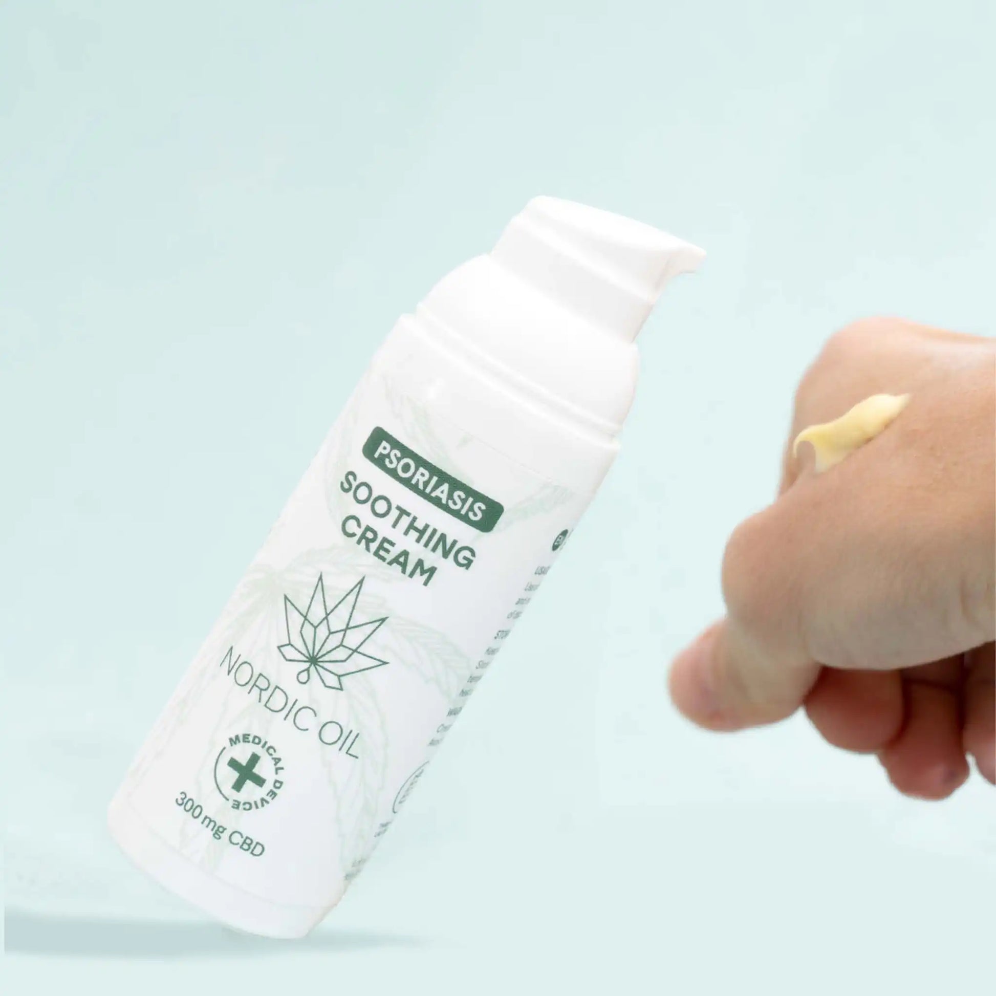 Psoriasis creme står diagonalt på en hvid baggrund og på den ene håndflade er cremen påført.