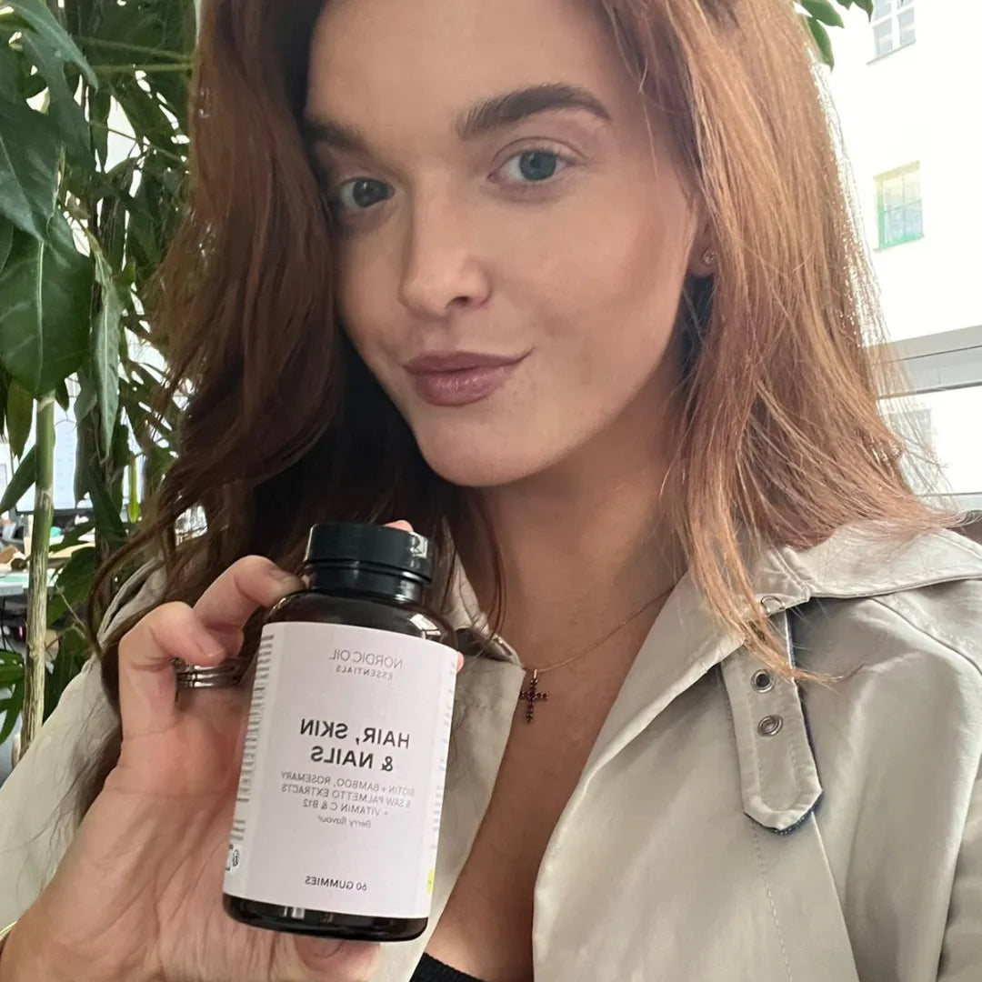 Kvinde, der holder en flaske Hair, Skin & Nails kosttilskud fra Nordic Oil.