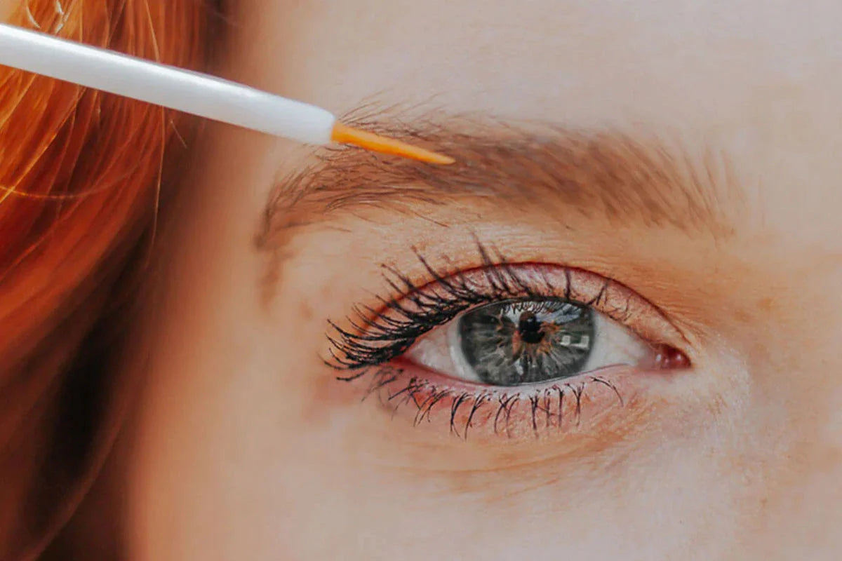 En kvinde påfører CBD Vippeserum + F-vitamin på sine øjenvipper.