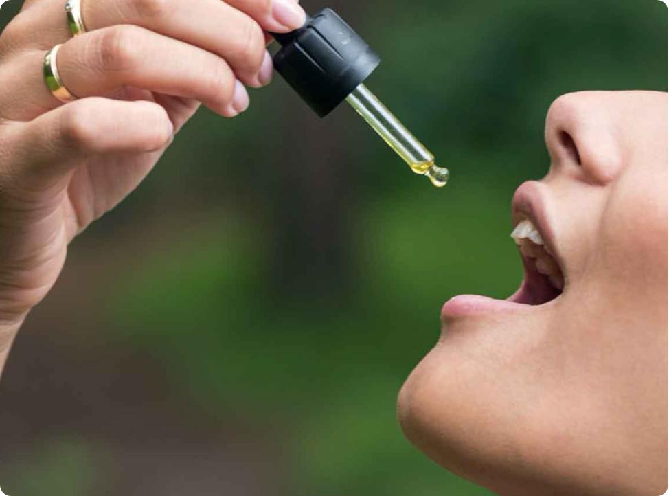 En kvinde drypper CBD Olie (15%) med curcumin i sin mund.