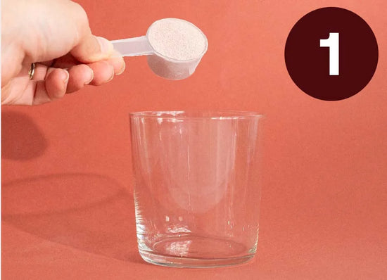 Hånd, der hælder hvidt pulver fra en måleske ned i et glas