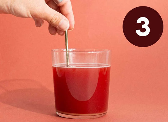 Hånd med pipette over et glas rød væske